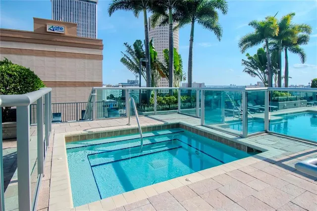 a view of swimming pool with a yard and palm trees