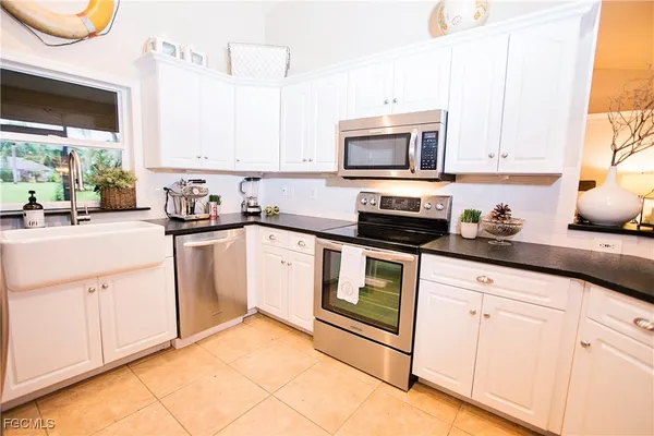 a kitchen with white cabinets stainless steel appliances a sink and a window