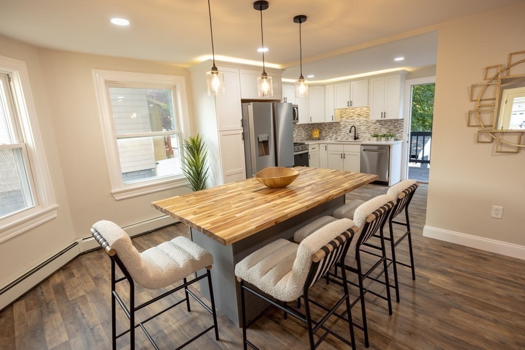 a dining room with stainless steel appliances kitchen island granite countertop a table chairs and a refrigerator