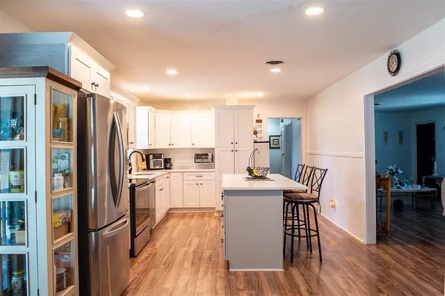 a kitchen with refrigerator and wooden floor