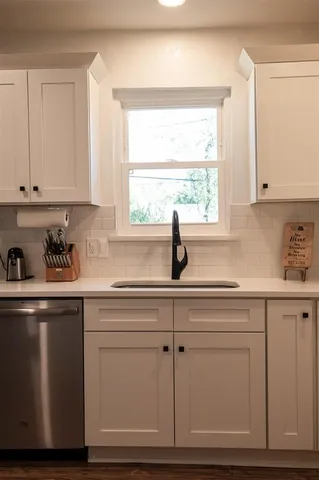 a kitchen with granite countertop white cabinets and a window
