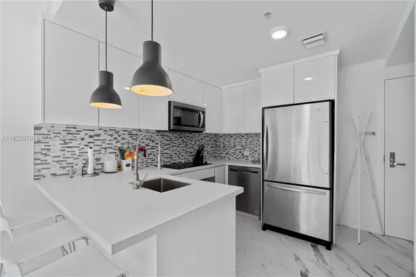a kitchen with stainless steel appliances a refrigerator a sink a stove and a wooden floors