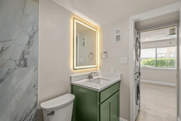 a bathroom with a sink vanity mirror and toilet
