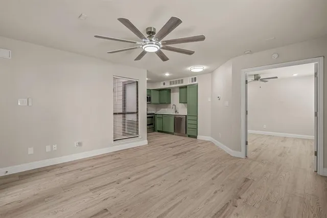 an empty room with wooden floor fan and windows