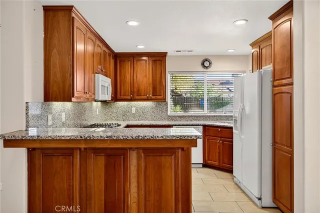 a kitchen with granite countertop wooden cabinets a refrigerator and dishwasher