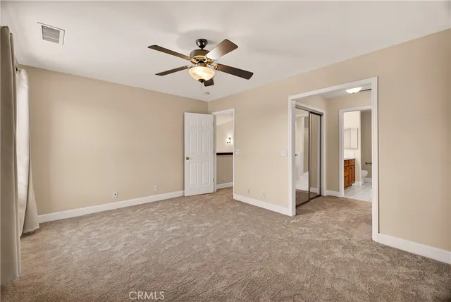 a view of an empty room and chandelier fan