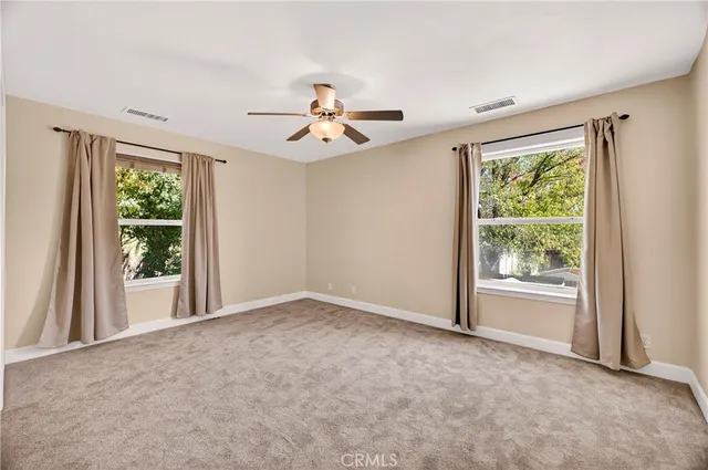 a view of a big room with windows and chandelier fan