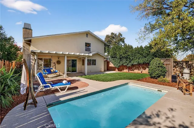 a backyard of a house with table and chairs plants and large tree