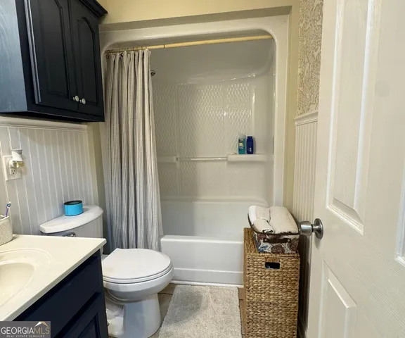 a bathroom with a granite countertop bathtub shower sink vanity and toilet