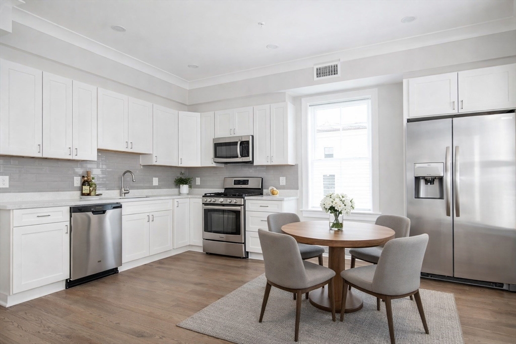 a kitchen with stainless steel appliances granite countertop a kitchen island hardwood floor sink and stove