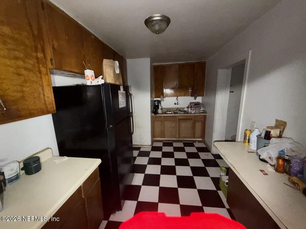 1926 Spring Drive Road Jacksonville, FL 32209 - Photo 17 of 19 a room with a black white checkered floor kitchen island a sink and a refrigerator