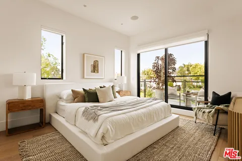 a bedroom with a bed and large windows