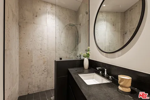 a bathroom with a granite countertop sink a mirror and a shower