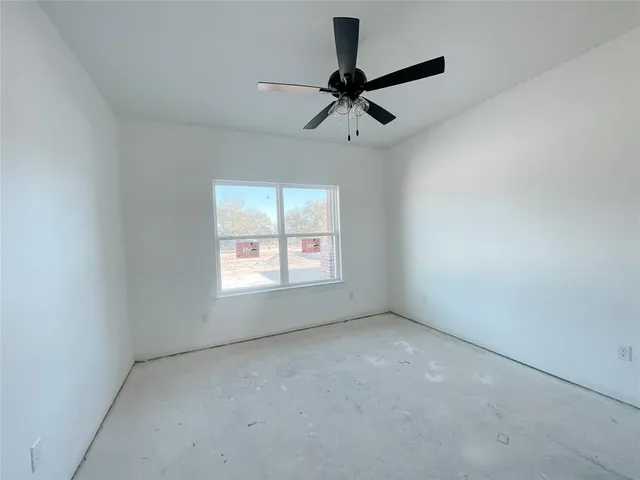 an empty room with a window and a fan