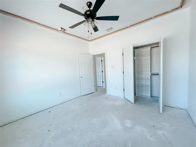 an empty room with a ceiling fan and carpet