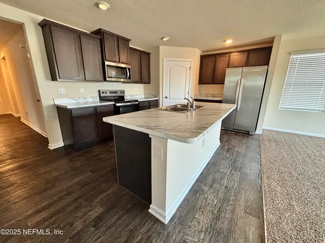 a kitchen with stainless steel appliances granite countertop a sink a stove and a refrigerator