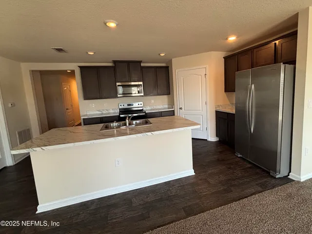 a large kitchen with stainless steel appliances a refrigerator a stove a sink a washer and dryer