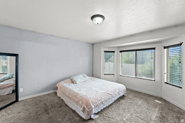 3396 Carmy Road Magna, UT 84044 - Photo 8 of 32 Bedroom featuring a bay window, neutral carpeting, light gray wall paint, and a semi-flush mount ceiling light