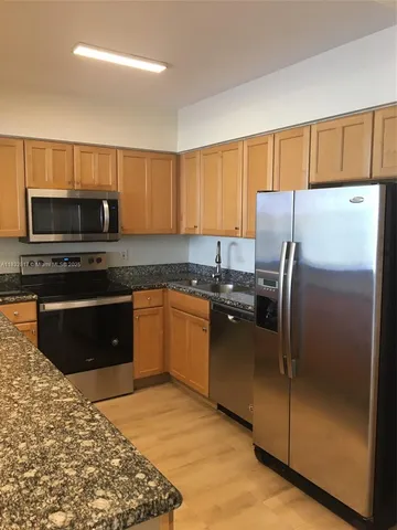 a kitchen with granite countertop a refrigerator and a stove top oven