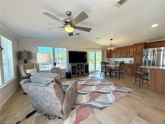 a living room with furniture a flat screen tv and kitchen view