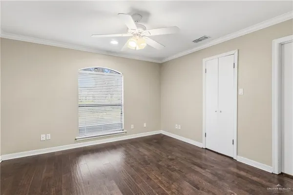 an empty room with wooden floor chandelier fan and windows