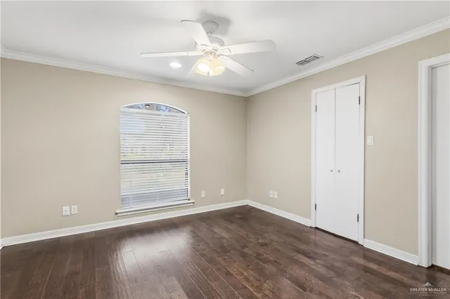 an empty room with wooden floor chandelier fan and windows