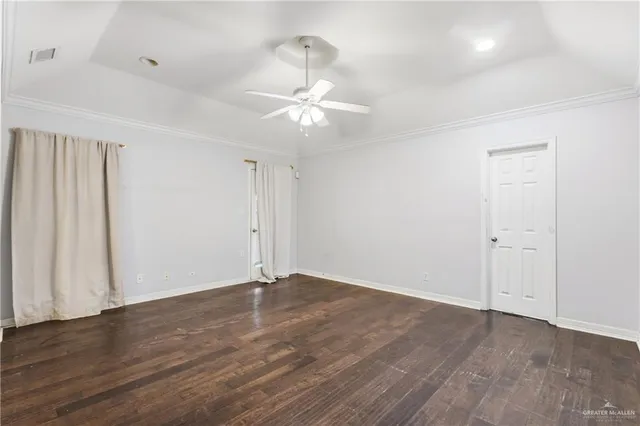 an empty room with wooden floor fan and window
