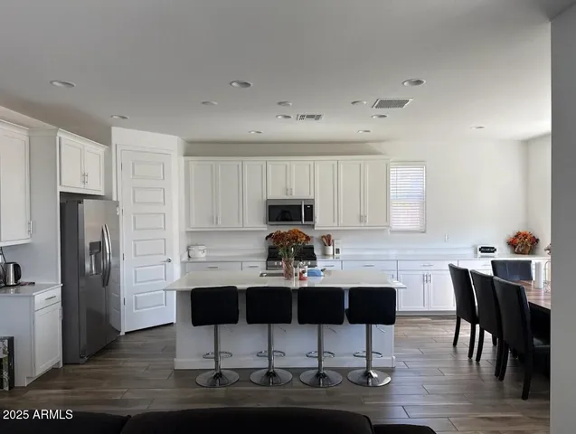 a kitchen with stainless steel appliances kitchen island granite countertop a dining table chairs and granite counter tops