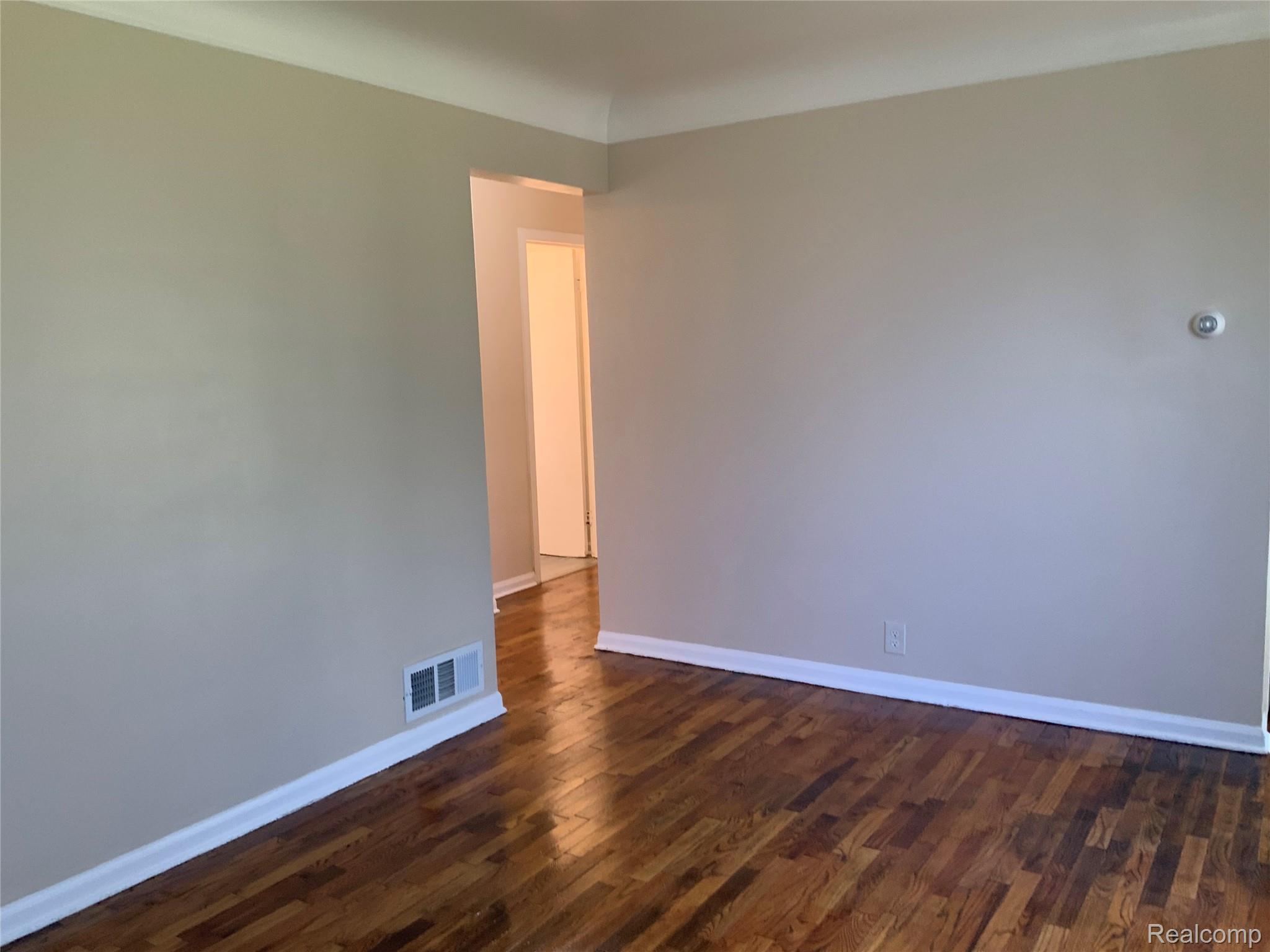 Hardwood flooring, light neutral wall paint, and white crown molding