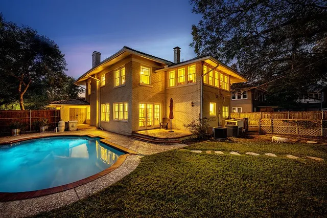 a view of a house with a wooden fence and a large tree