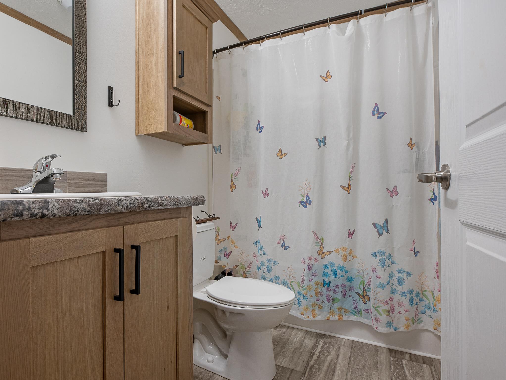 1040 Round Butte Road, Unit 34 Ronan, MT 59864 - Photo 27 of 30 Full bathroom featuring vanity, shower / bath combo with shower curtain, wood-type flooring, and toilet