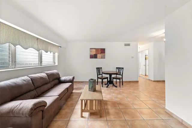 a living room with furniture and a dining table with rug