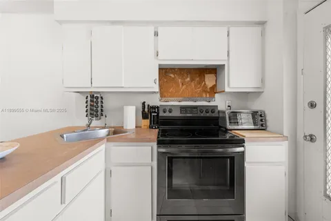a kitchen with granite countertop a stove sink and cabinets