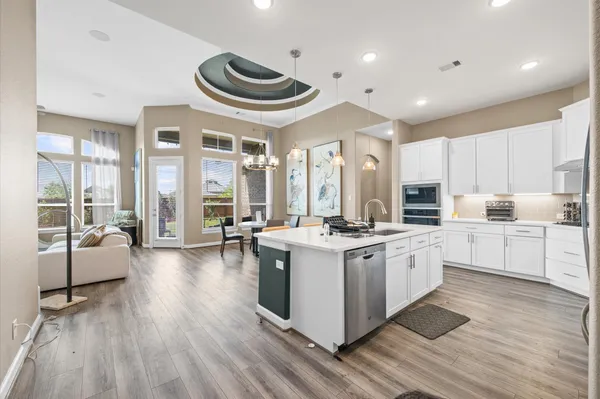 a kitchen with stainless steel appliances a stove a sink a refrigerator and white cabinets with wooden floor