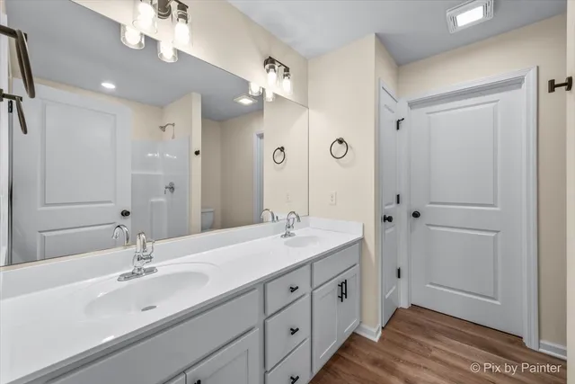 a spacious bathroom with a double vanity sink a large mirror and shower