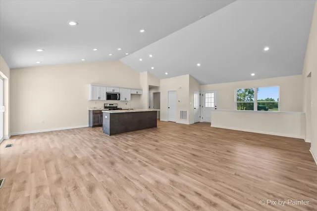 a view of kitchen with stainless steel appliances granite countertop a refrigerator and a stove top oven