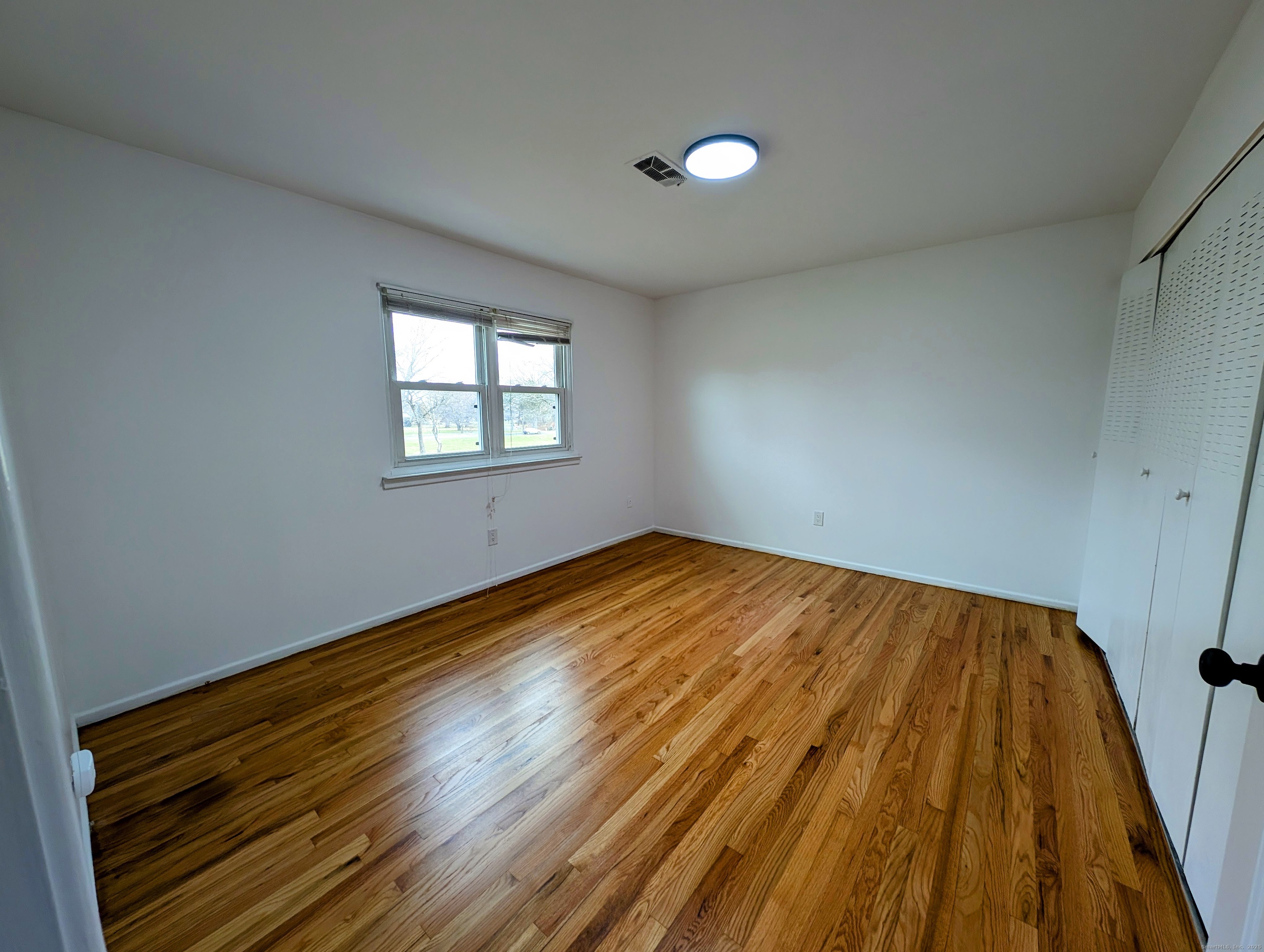23 Shea Avenue, Unit 23 Milford, CT 06460 - Photo 11 of 16 an empty room with wooden floor and windows