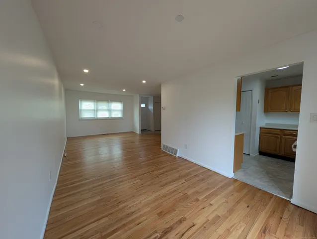 a view of a hallway with wooden floor and a kitchen