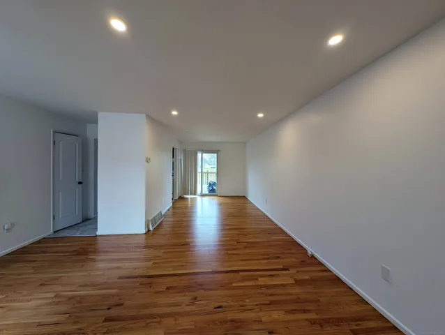 a view of an empty room with wooden floor and window
