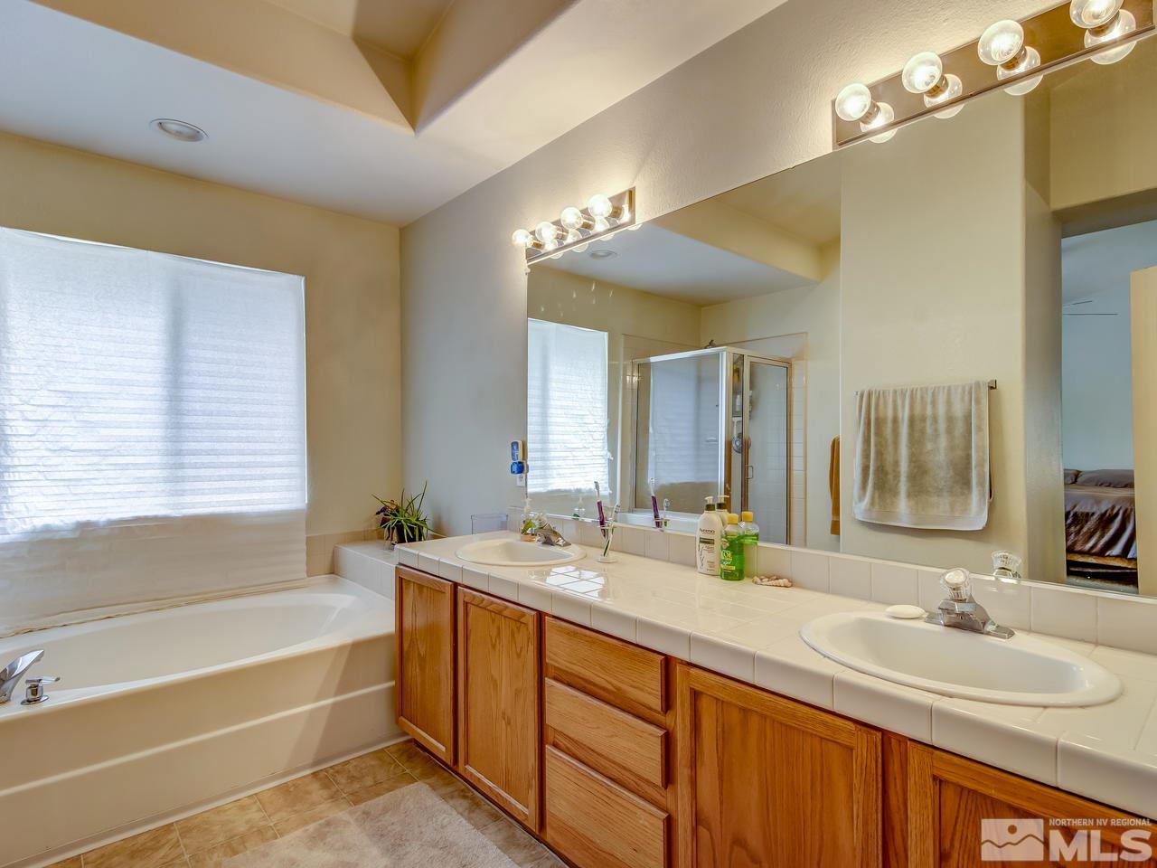 9665 Oakley Lane Reno, NV 89521 - Photo 15 of 23 a bathroom with double vanity sinks a large mirror and a bathtub