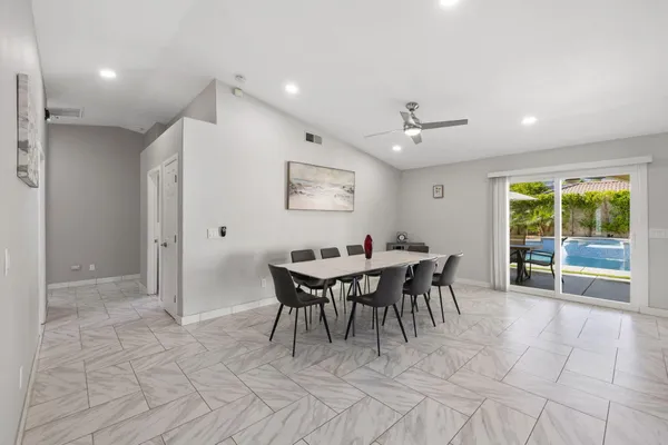 a kitchen with stainless steel appliances kitchen island granite countertop a refrigerator a stove a sink a dining table and chairs with wooden floor