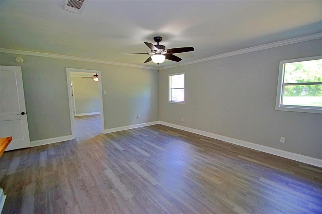 104 Orr Street Sarepta, LA 71071 - Photo 6 of 24 an empty room with wooden floor ceiling fan and windows