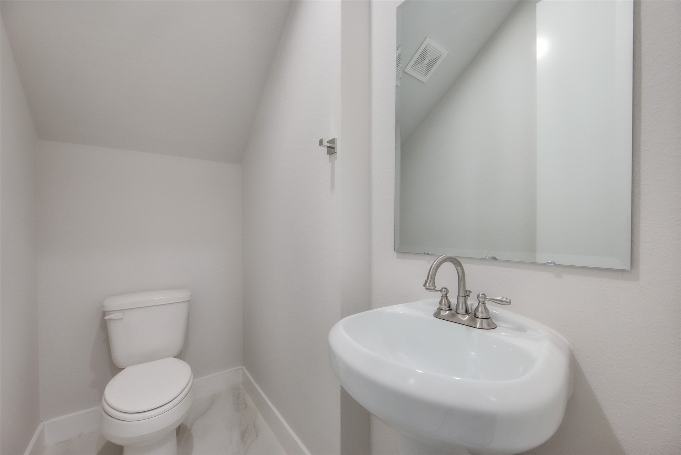 853 Mansfield Street, Unit A Houston, TX 77091 - Photo 7 of 16 This sleek half bathroom offers a minimalist design with a pedestal sink and modern fixtures. The clean lines and bright lighting create a fresh and inviting atmosphere, perfect for guests and everyday use.