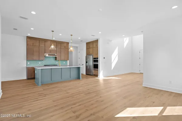 a large kitchen with stainless steel appliances a large counter top a refrigerator and a sink