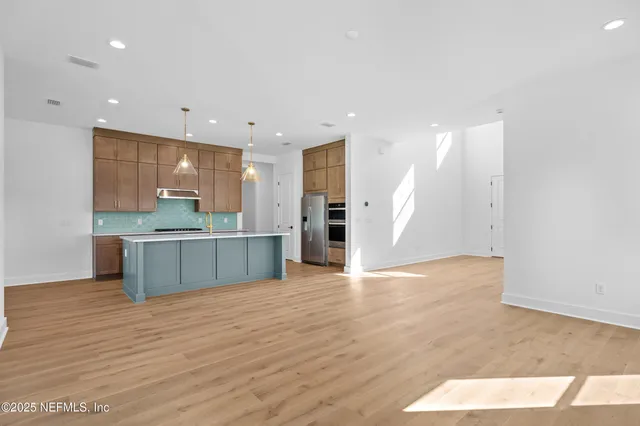 a large kitchen with stainless steel appliances a large counter top a refrigerator and a sink