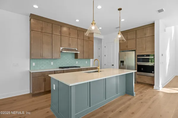 a large kitchen with a large counter top a sink stainless steel appliances and cabinets