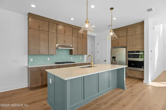a large kitchen with a large counter top a sink stainless steel appliances and cabinets
