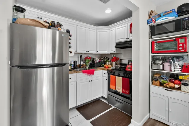 a kitchen with white cabinets and appliances