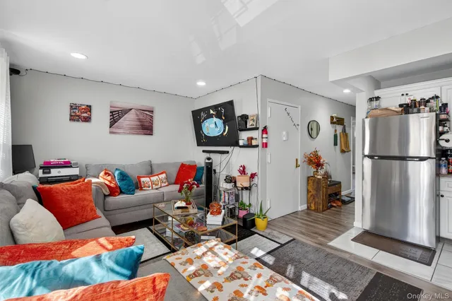 a living room with furniture and a refrigerator