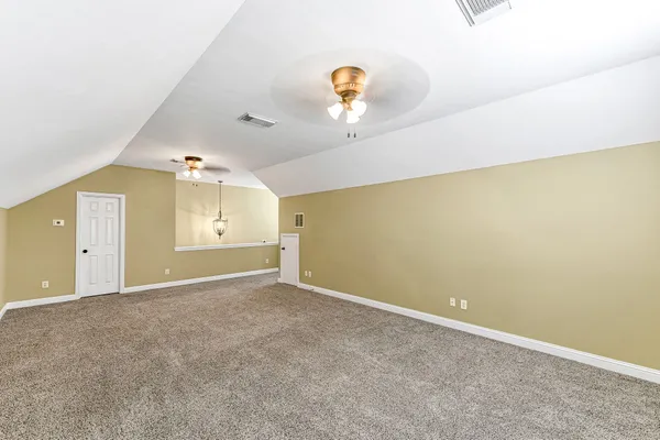 an empty room with a chandelier fan and wooden floor